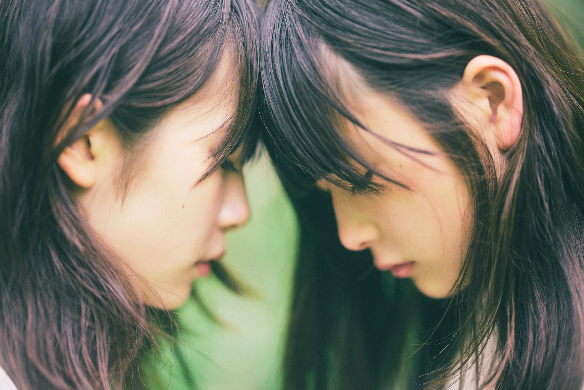 女性二人が下を向きながら互いの額を当てている
