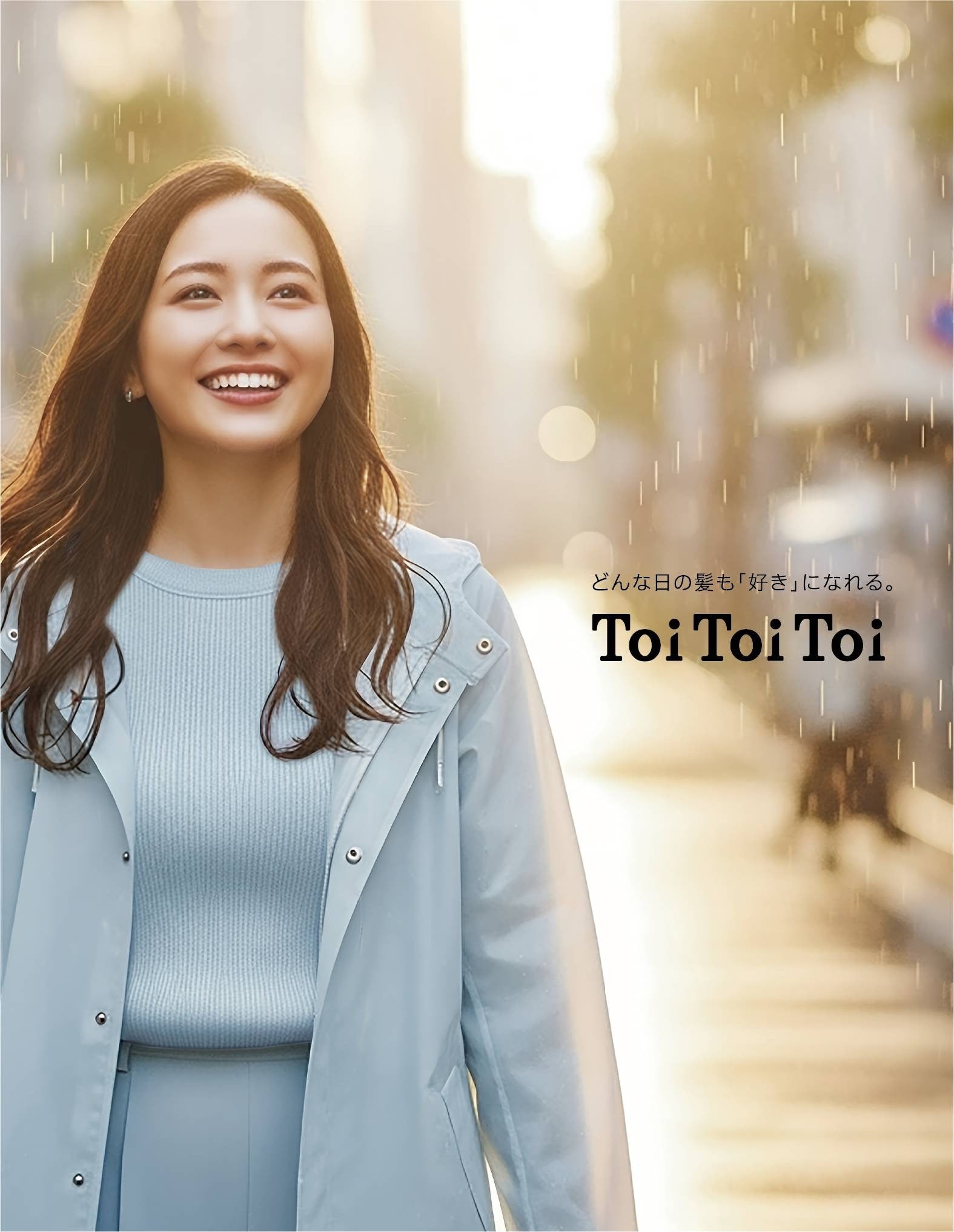 雨が降っている中、街中にいる女性が笑顔で立っている。